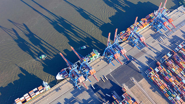 Vogelperspektive auf eine Kaimauer mit Containerbrücken und Frachtschiffen als Grundlage für moderne Hafensimulationen der HHLA.